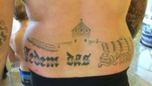 Ein Tattoo mit einem stilisierten Konzentrationslager (KZ) am Rücken, dazu ein die Opfer verhöhnender Spruch...