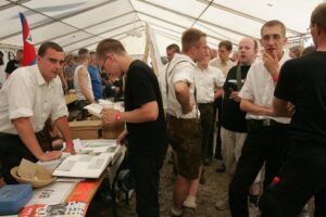 BfJ-Stand beim NPD-Pressefest in Mücka/Sachsen, 7.8.2004. In Lederhose Stefan Magnet im Gespräch mit dem Neonazi Oliver-Gerd Raninger (© issos.media)