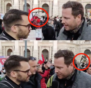 Scharfmüller interviewt Schnedlitz – im Hintergrund spaziert Demoteilnehmer mit Galgen vorbei (Demo 20.11.21; Screenshot Video Info-Direkt)